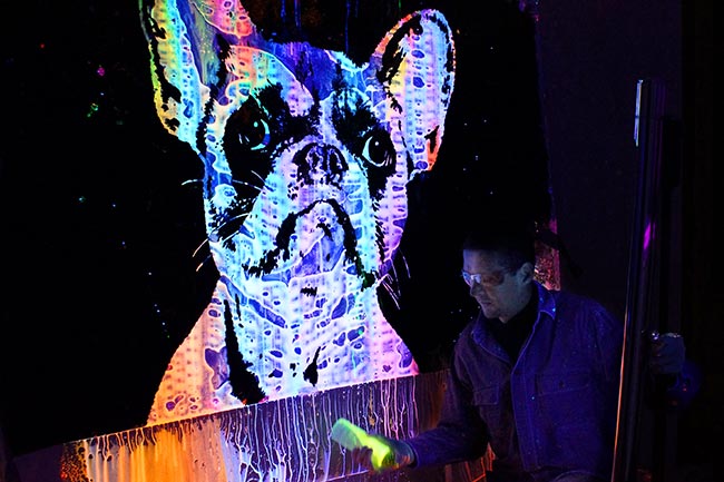 The artist mixing fluorescent colors in front of his artwork
